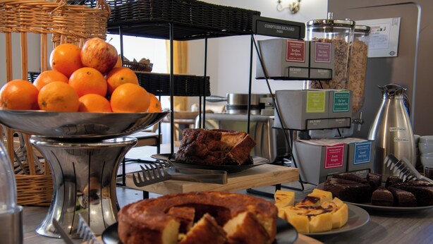 A buffet with various food items including oranges, a cake, and brownies.