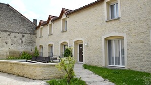 A stone building with a courtyard, outdoor seating, and a small garden.
