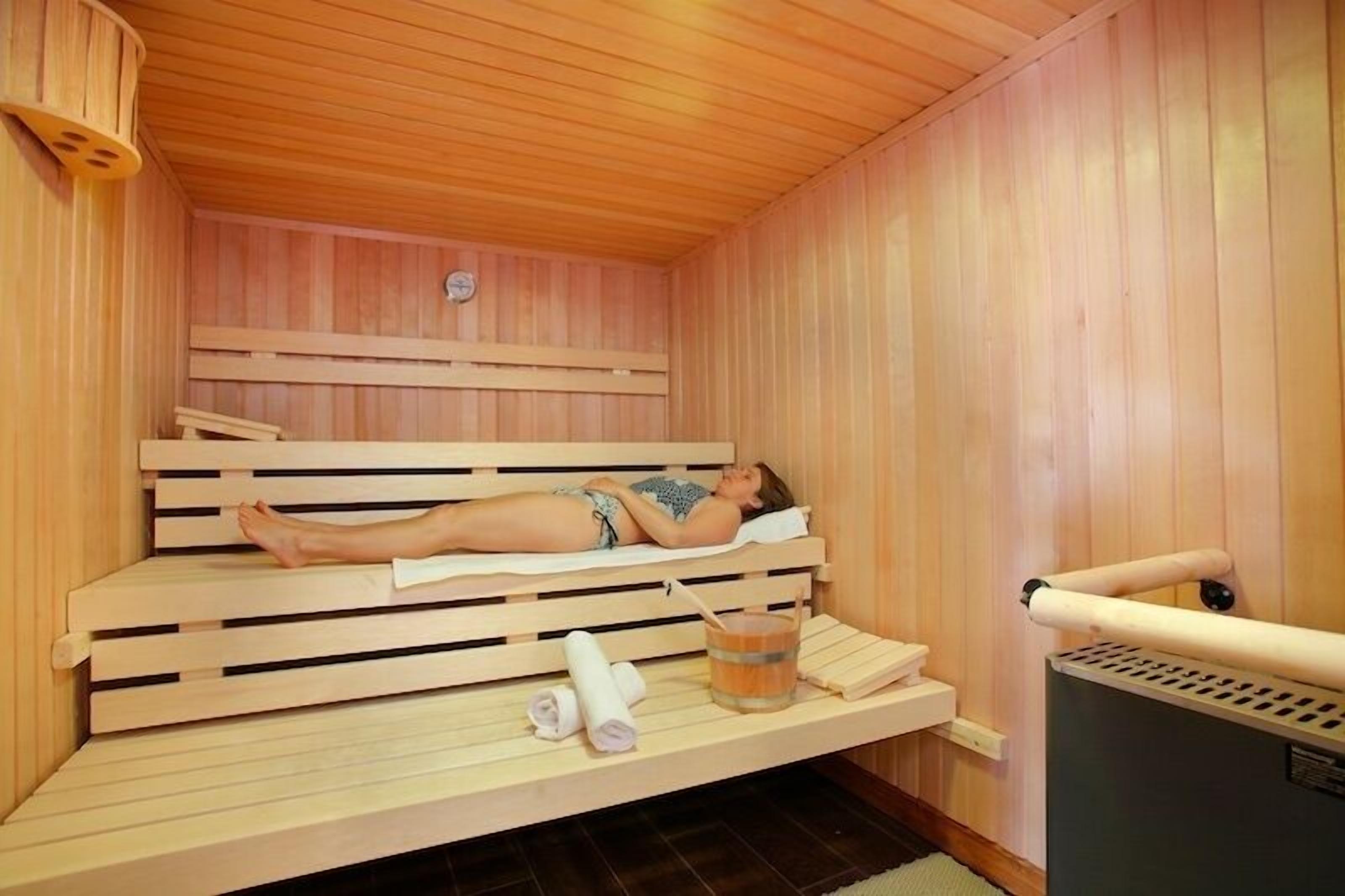 Una sala de sauna con bancos de madera, un reloj y un calentador de sauna.