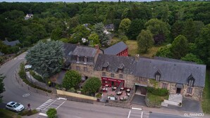 A stone building with a red facade, a restaurant, and a spa. - Hotel Le Relais De Broceliande (Paimpont)