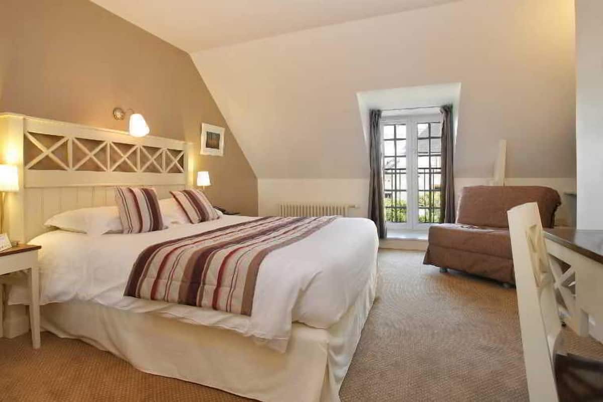 Ein Hotelzimmer mit Bett, Schreibtisch, Stuhl, Heizkörper und Fenster.