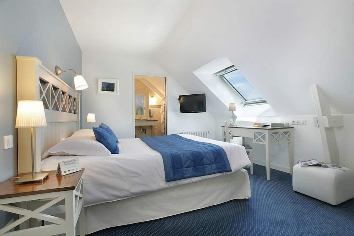 Ein Hotelzimmer mit Bett, Schreibtisch und einem Oberlicht.