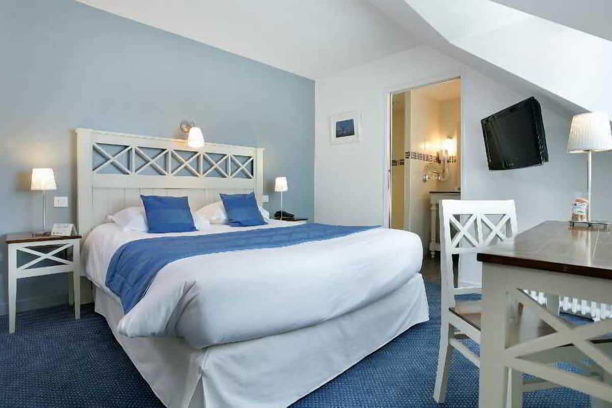 Ein Schlafzimmer mit einem Bett, Nachttischen, einem Schreibtisch und einem Fernseher.