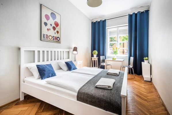 A hotel room with two beds, a desk, and a chair. - Flamingo Hostel (Kraków)