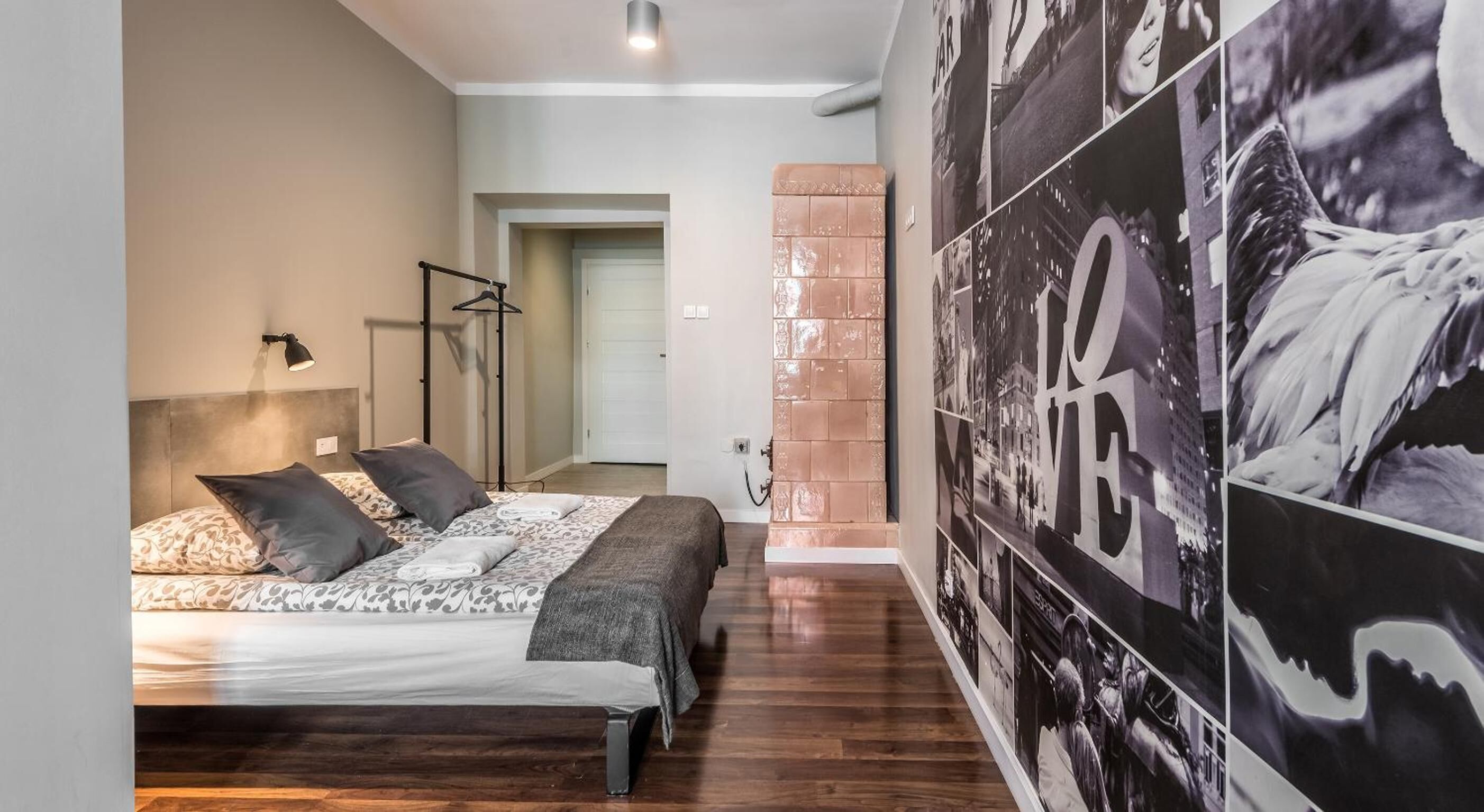 A bedroom with a bed, a floor lamp, and a wall with a large poster.