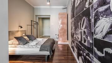 A bedroom with a bed, a floor lamp, and a wall with a large poster.