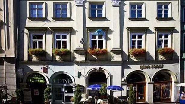 Un edificio con fachada clásica, varias ventanas y terraza al aire libre con sombrillas.