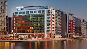 A modern hotel with a distinctive facade, multiple floors, and a waterfront view. - Kordon Hotel Pasaport (Izmir)