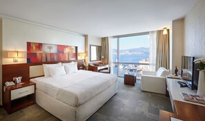 Habitación de hotel con una cama grande, un escritorio, una silla y vistas al mar.
