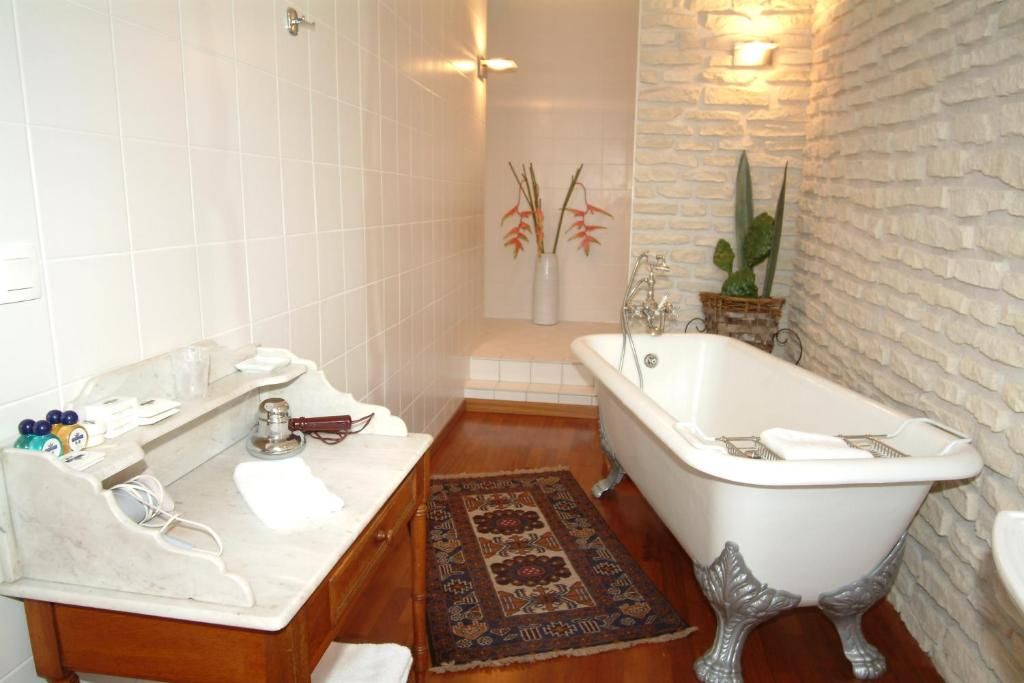 Un baño con una bañera blanca, un tocador de madera y un tapete estampado.