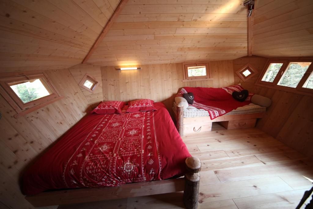 Et soveværelse i en træhytte med to senge, et vindue og et skråt loft.