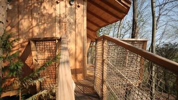 A wooden treehouse with a wooden deck and a rope ladder.