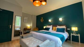 A hotel room with a large bed, a sitting area, and a desk.