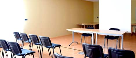 A conference room with a whiteboard, a table, and several chairs arranged around it.