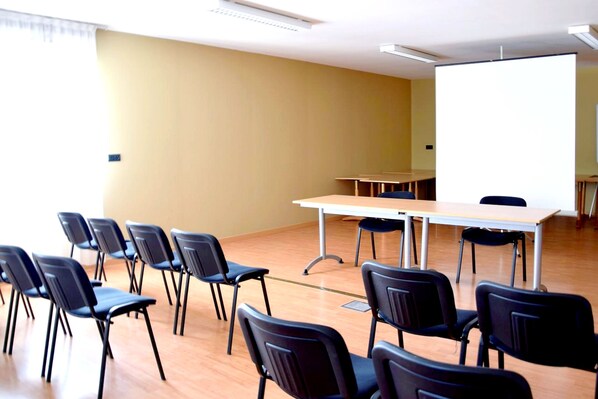 A conference room with a whiteboard, a table, and several chairs arranged around it. - Logis De France Des Sources (Creney-pres-Troyes)