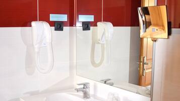 Un baño moderno con un espejo grande, dos secadores de manos blancos, un lavabo y un perchero para toallas.