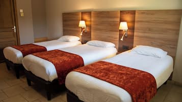 Ein Hotelzimmer mit drei Einzelbetten, jedes mit einer roten Tagesdecke und weißer Bettwäsche.