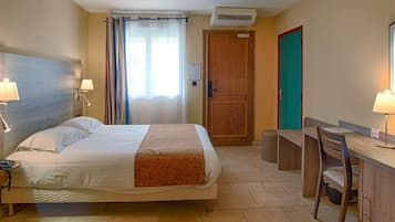 Une chambre d’hôtel comprenant un lit, des lampes de chevet, un bureau avec une chaise, un miroir et une porte.