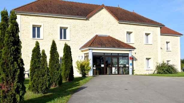 A stone building with a central entrance, multiple windows, and a paved driveway. - Logis De France Des Sources (Creney-pres-Troyes)
