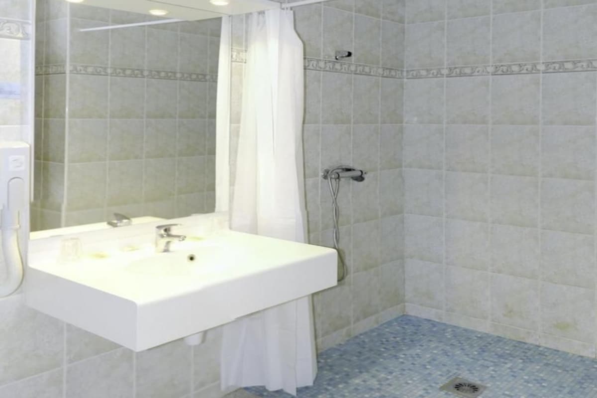 A bathroom with a white sink, a mirror, and a shower.