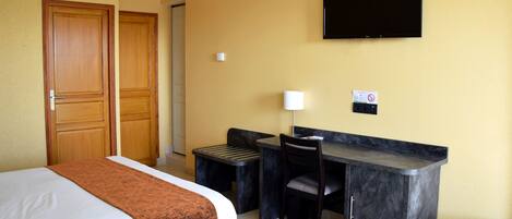 A hotel room with two beds, a desk, a chair, a television, and a small table.