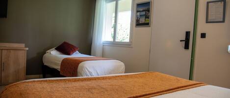 A bedroom with a bed, a window with curtains, a door, and a wall-mounted picture.