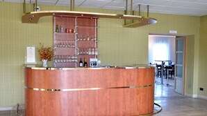 A bar area with a copper-colored counter, shelves with glasses, and a vase with flowers. - Logis De France Des Sources (Creney-pres-Troyes)
