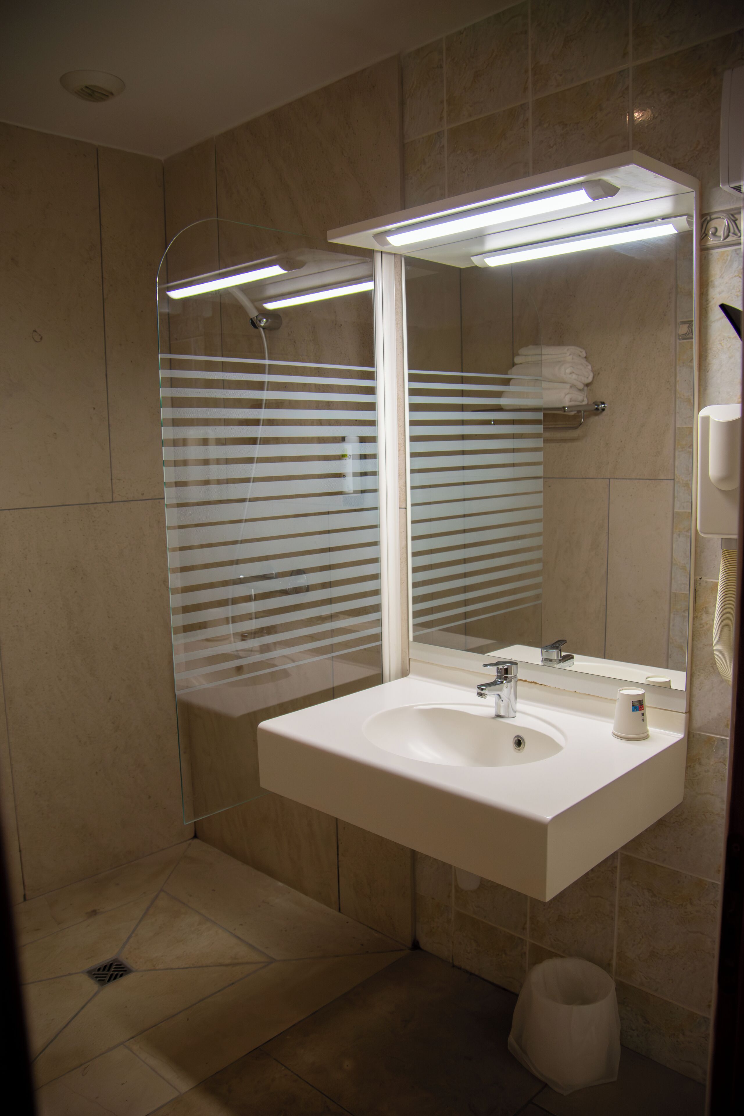 Un baño moderno con un espejo grande, un lavamanos y una zona de ducha.