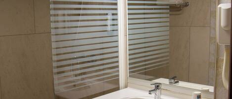 A modern bathroom with a large mirror, a sink, and a shower area.