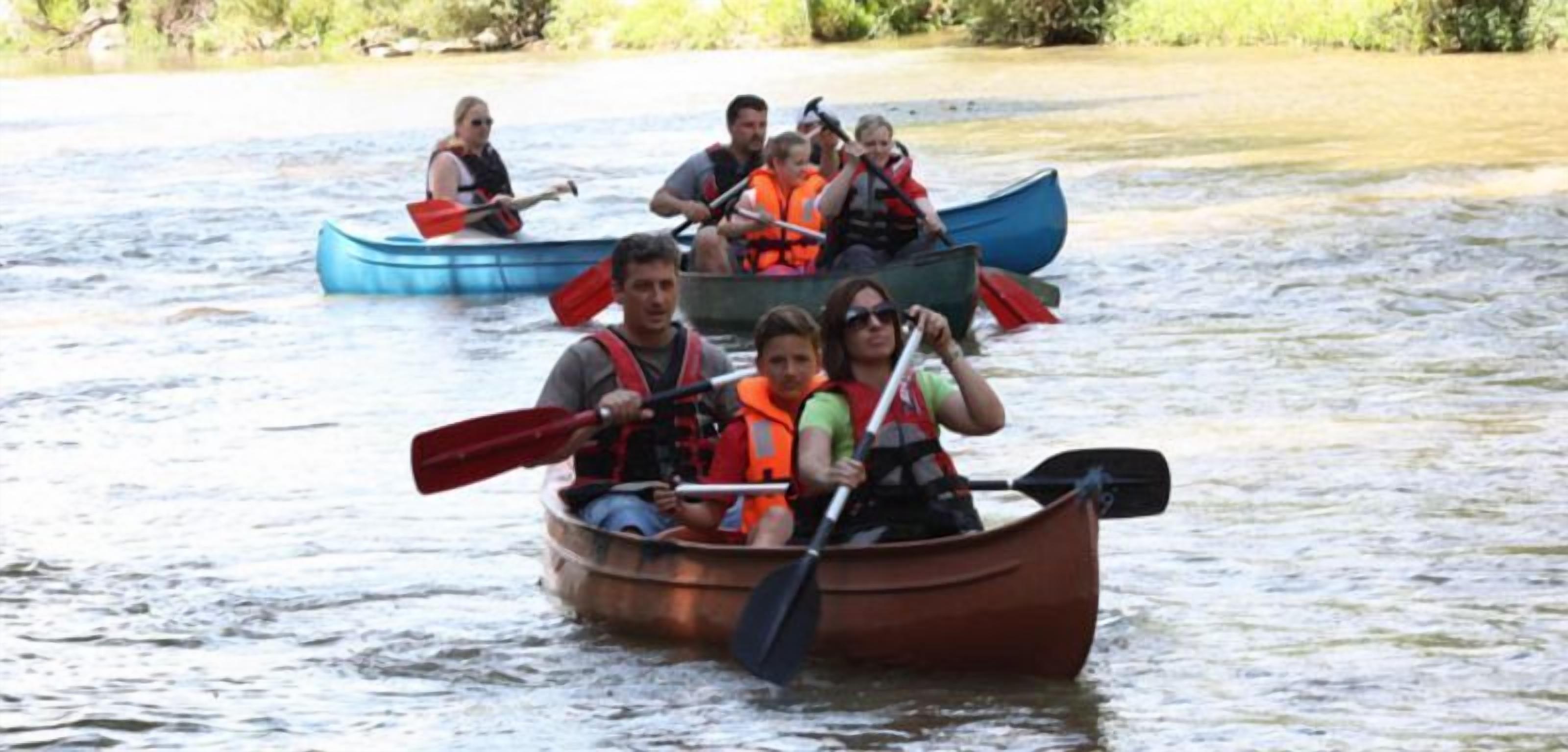 A group of people in canoes on a calm body of water.