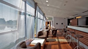 Um interior moderno com área de bar, assentos e grandes janelas.