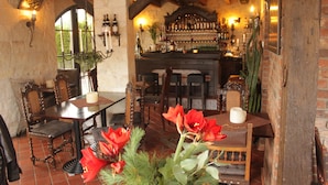 Una zona de bar rústica con muebles de madera, pared de ladrillo y una variedad de botellas y vasos.