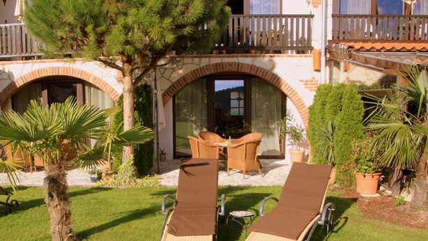 Un patio con asientos al aire libre, una palmera y un edificio con balcón.