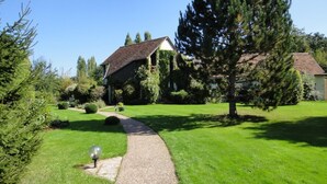 A house with a gravel pathway leading to a wooden door, surrounded by a well-maintained lawn and trees. - Domaine de l'Arbrelle (Amboise)
