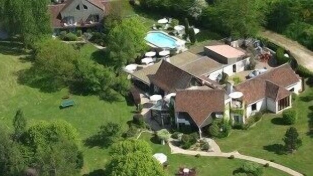 An aerial view of a large estate with multiple buildings, a swimming pool, and well-maintained lawns.