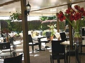 An outdoor dining area with tables and chairs, surrounded by potted plants and a canopy. - Domaine de l'Arbrelle (Amboise)