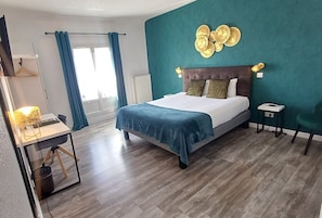 A modern bedroom with a large bed, a desk, and a chair. - Hôtel Le Cerf (Briare)