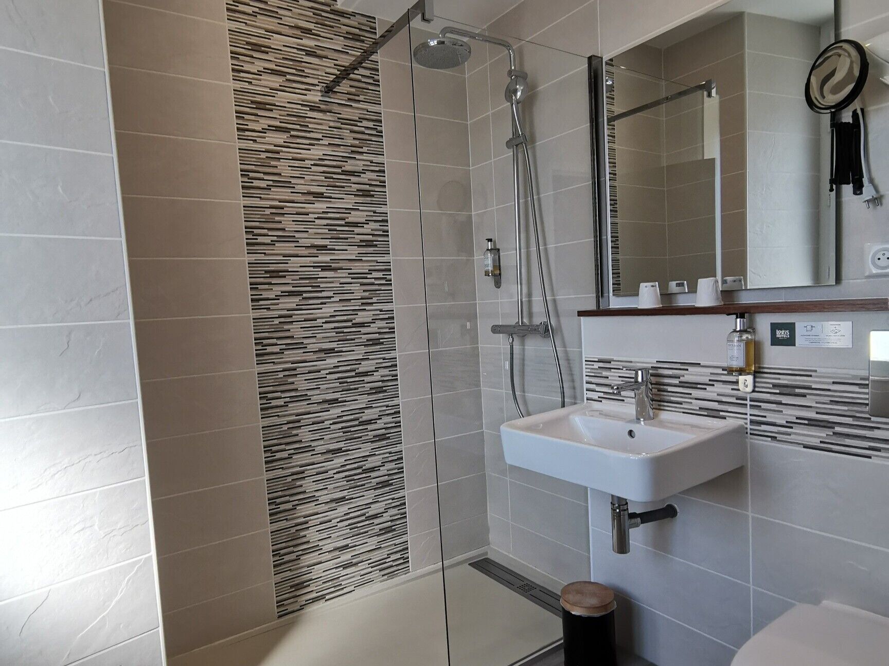 Une salle de bain moderne avec une douche, un lavabo et un miroir.