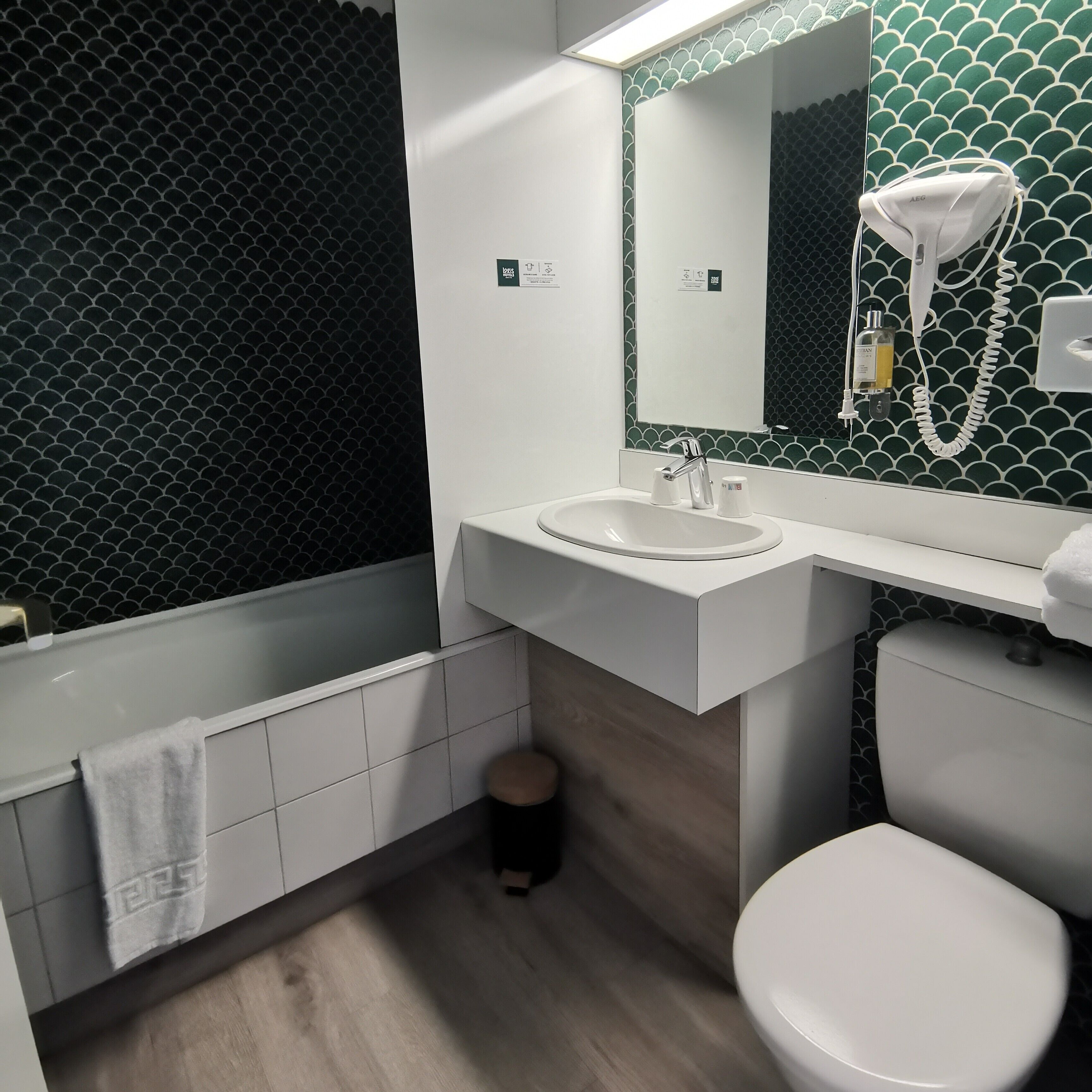 Une salle de bain moderne avec un lavabo blanc, un miroir et des toilettes.
