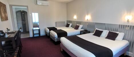 A hotel room with two beds, a desk, and a shower area.