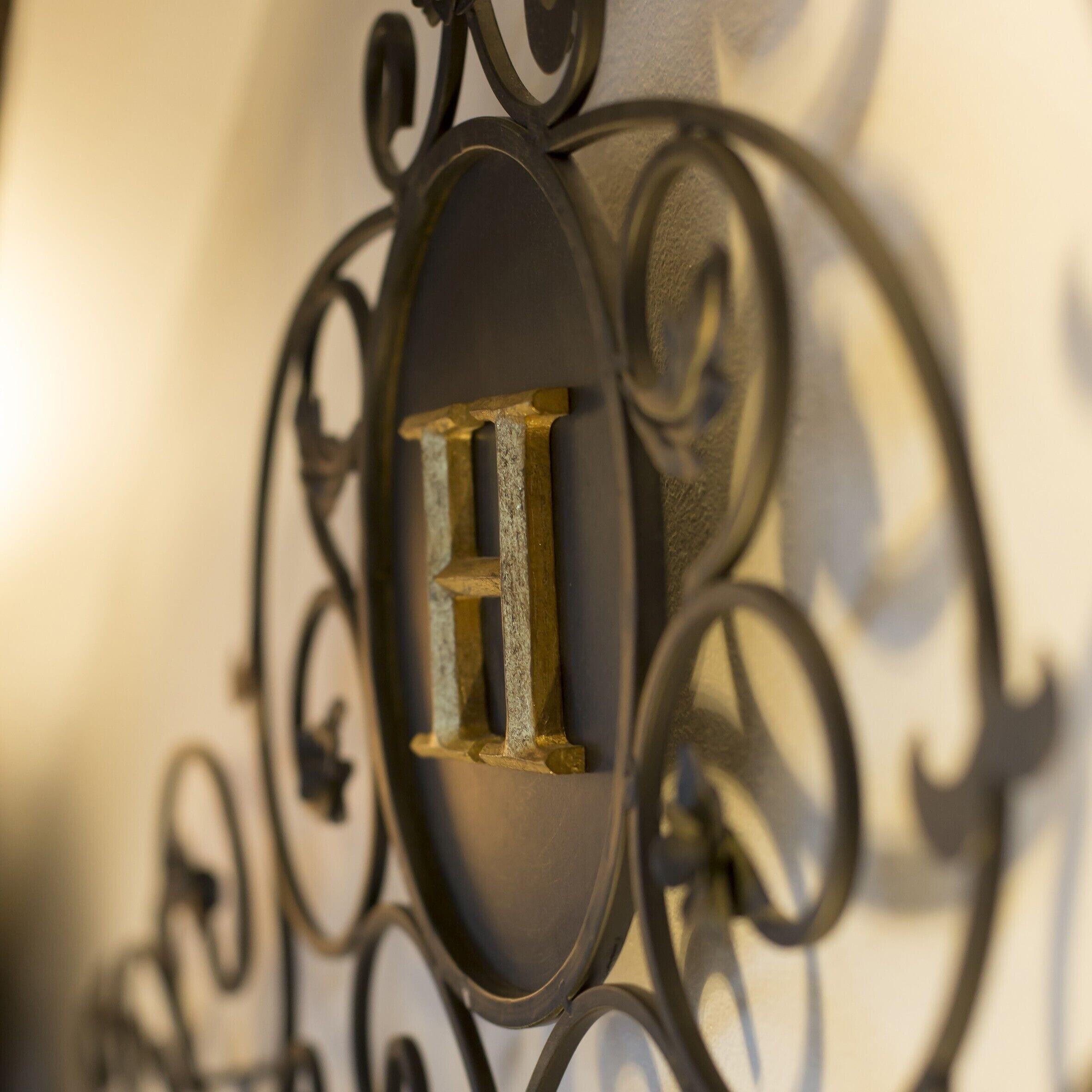 A close-up of a metal sign with a letter 'H' on a wall.