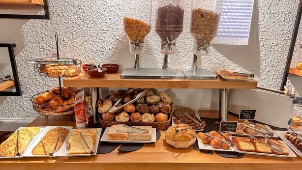 Un bufé de desayuno con panes, pasteles y diversas opciones para untar.