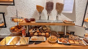 A breakfast buffet with various breads, pastries, and spreads. - Hôtel Le Cerf (Briare)