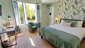 Un dormitorio con cama, escritorio, silla y ventana con cortinas.