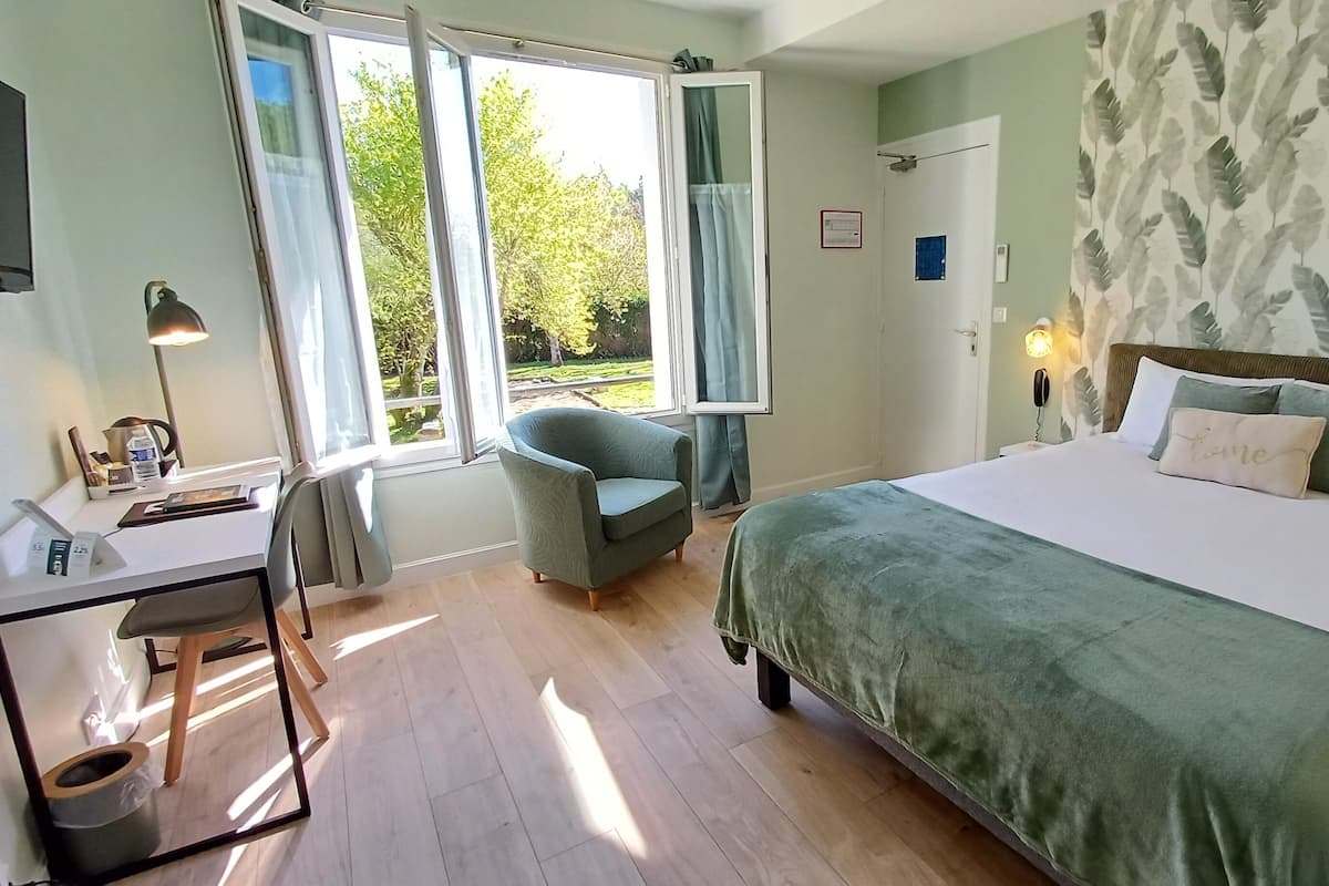 A bedroom with a bed, a desk, a chair, and a window with curtains.