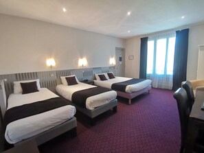 A hotel room with three beds, a desk, and a chair. - Hôtel Le Cerf (Briare)