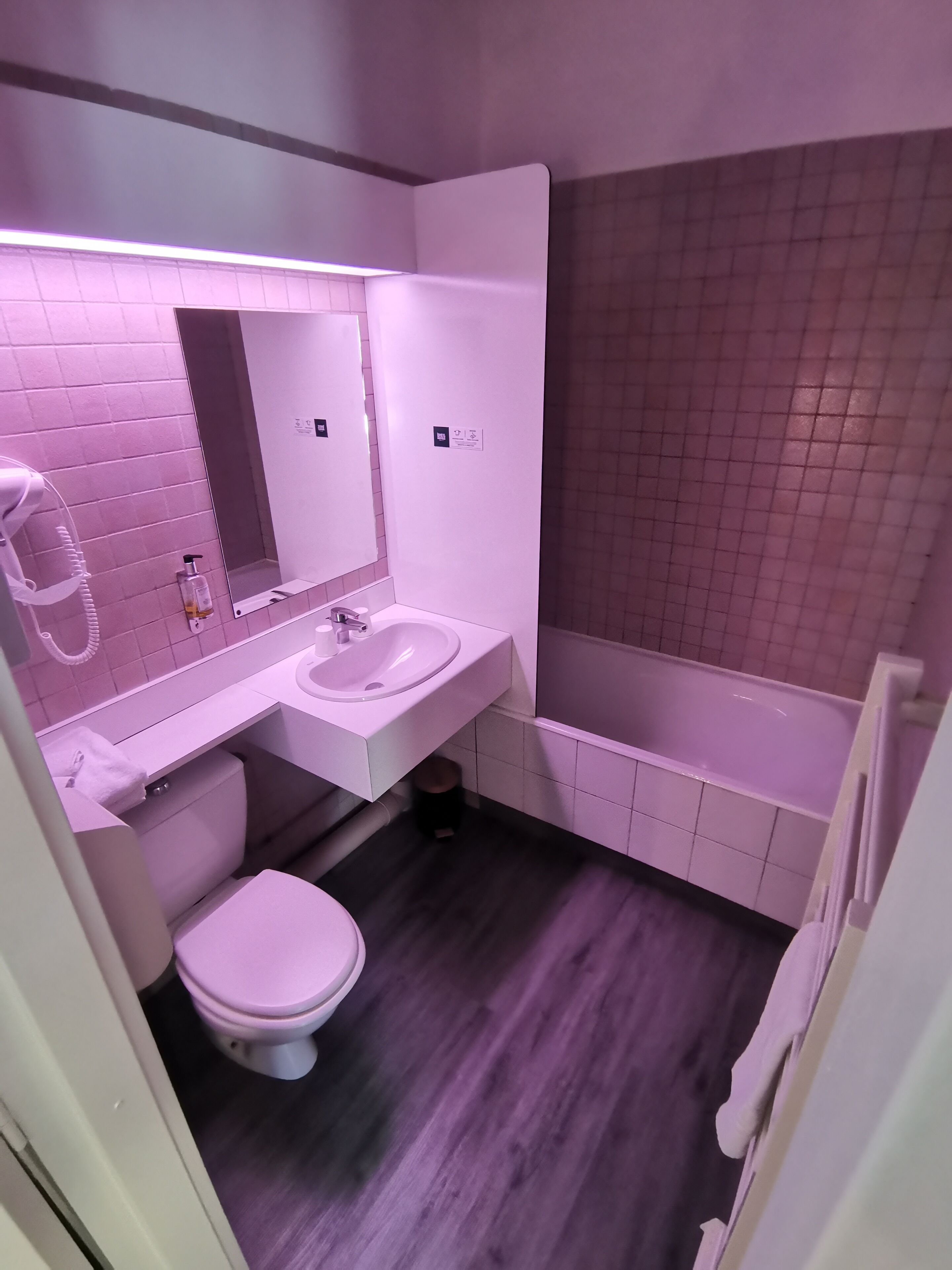 A bathroom with a white sink, mirror, and toilet, and a bathtub.