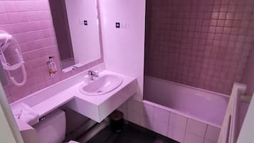 A bathroom with a white sink, mirror, and toilet, and a bathtub.