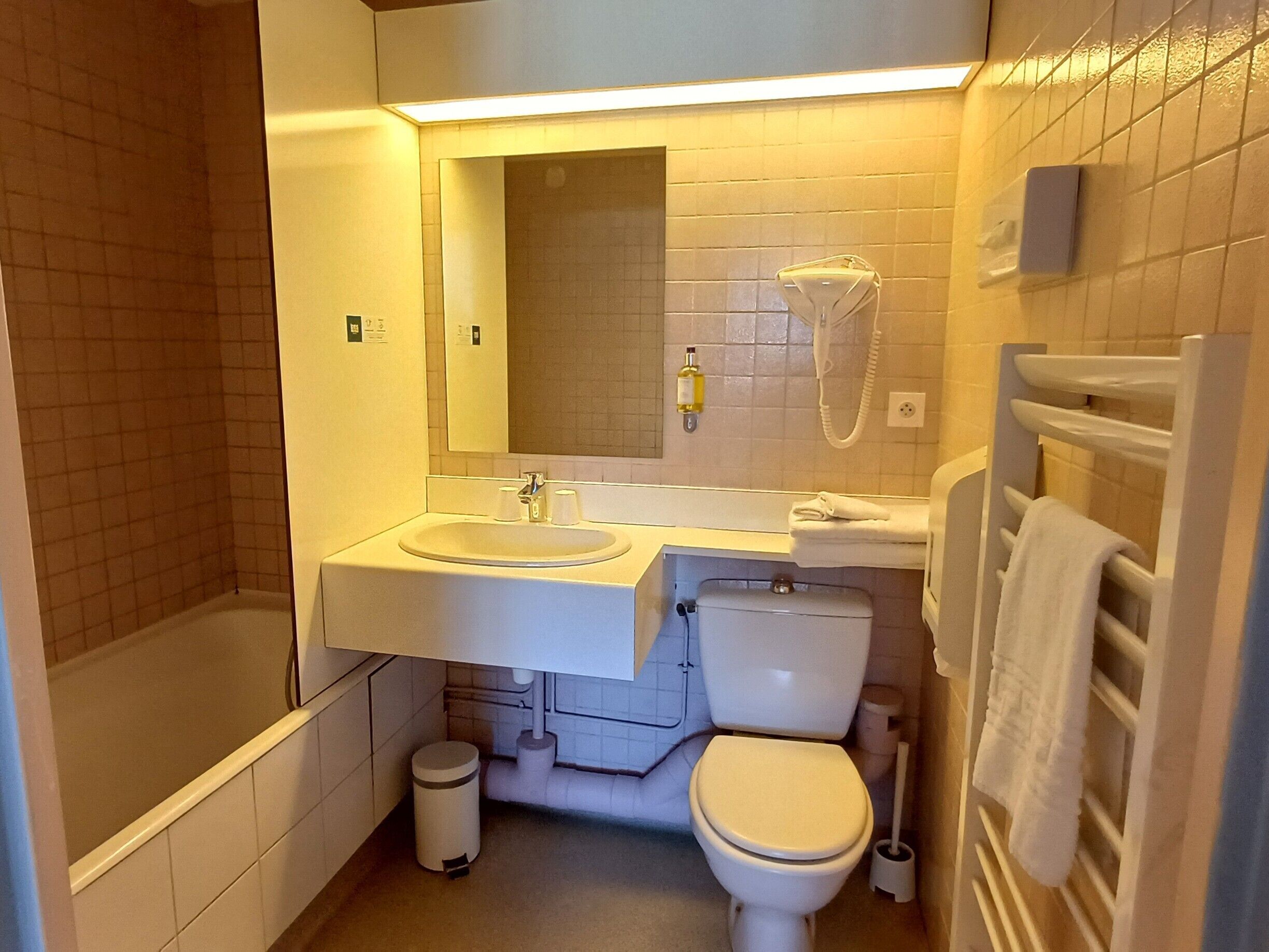 Un bagno con vasca, water, lavandino e porta asciugamani.