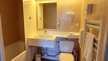 Un bagno con vasca, water, lavandino e porta asciugamani.